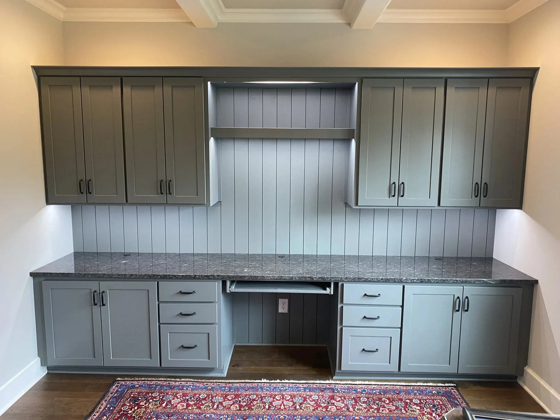 Custom office cabinetry with beadboard back panel and stone countertop